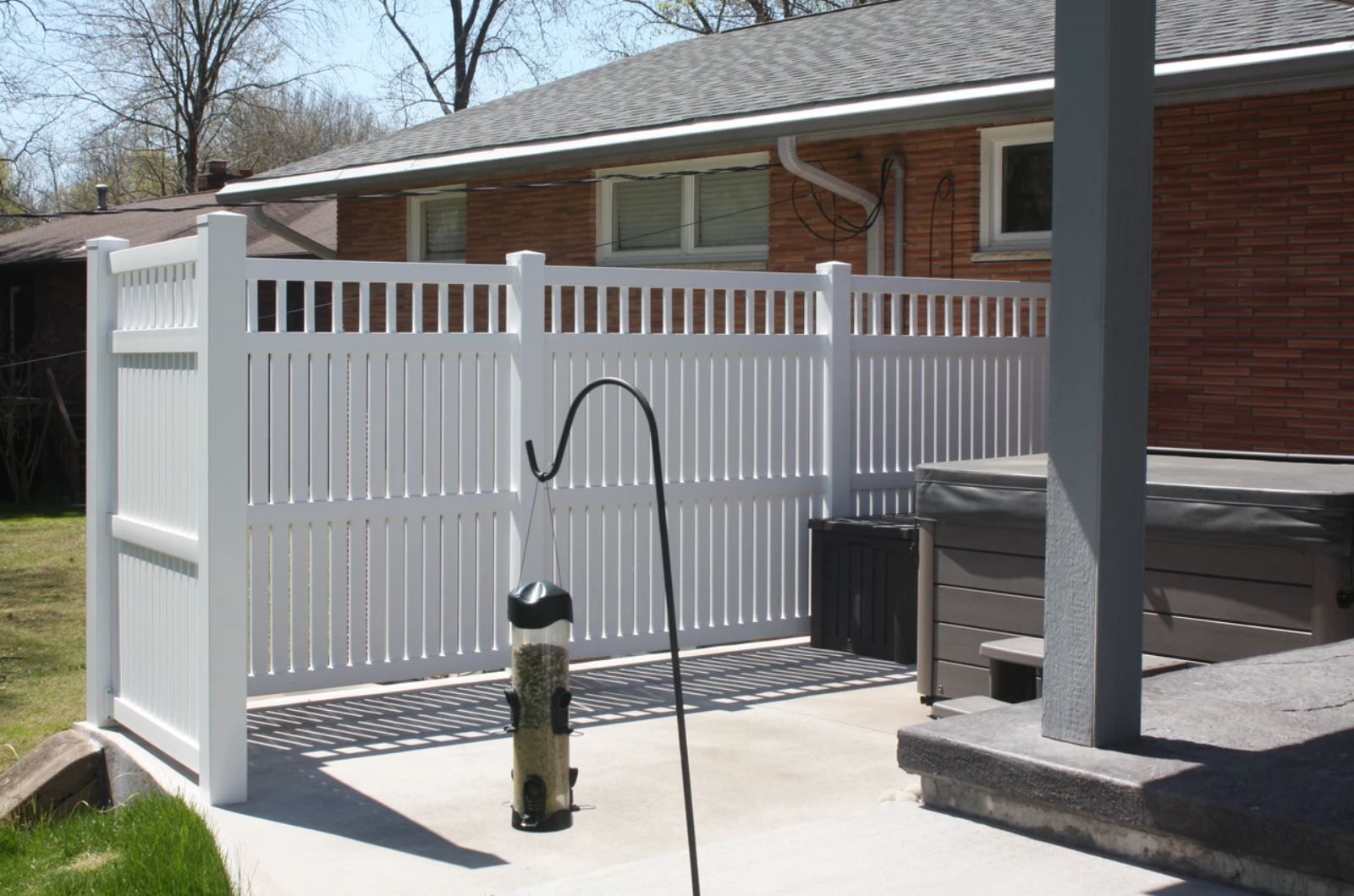 A white fence is in front of a brick house.