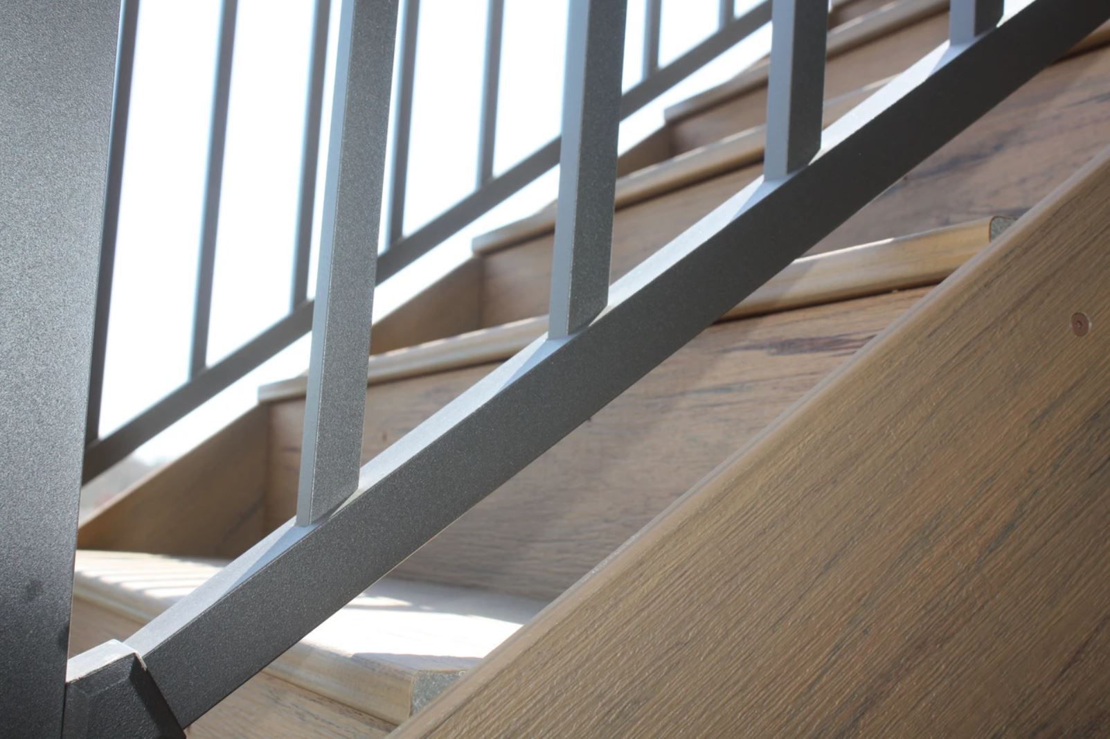 A close up of a metal railing on a wooden staircase