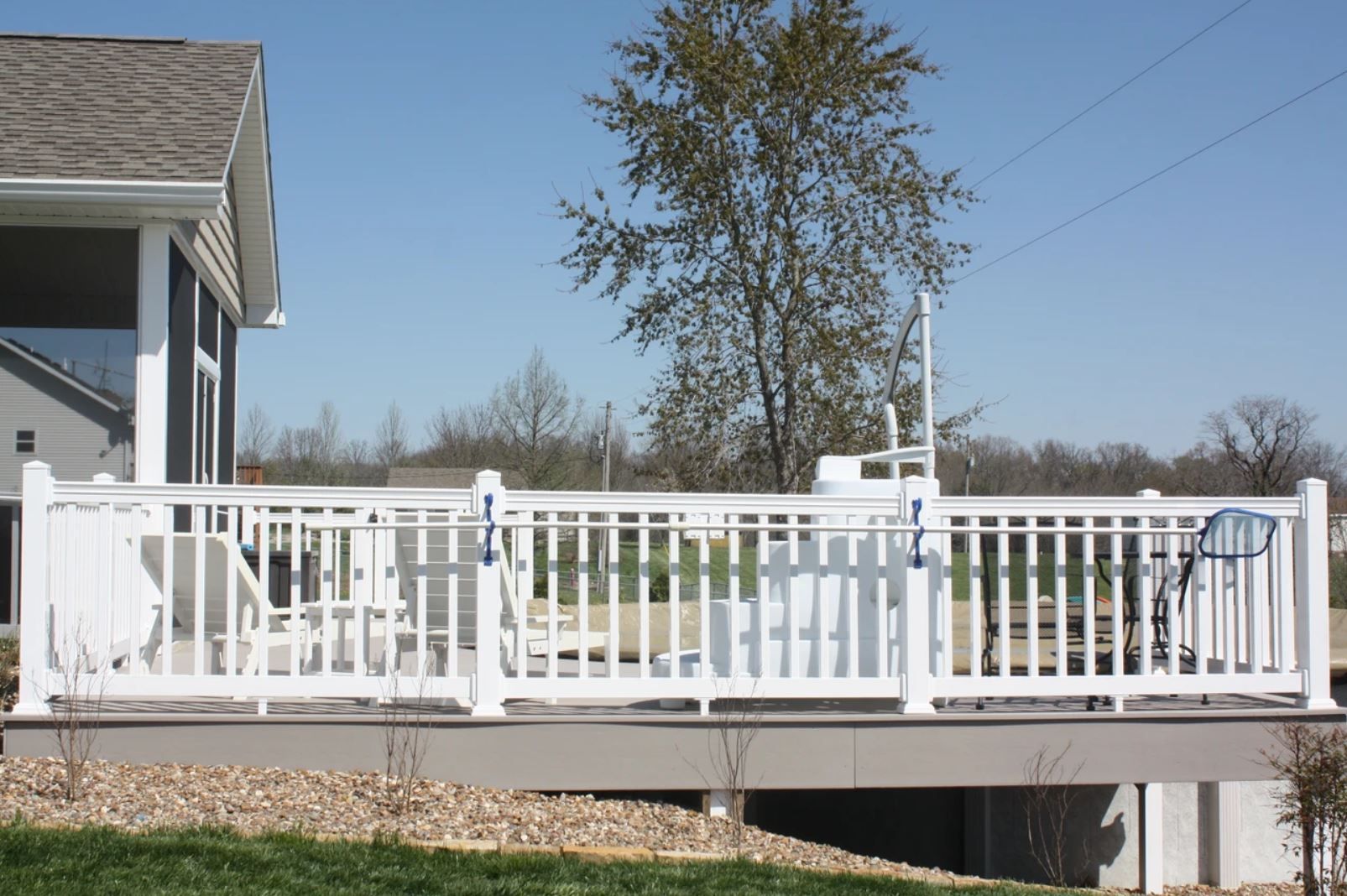 A white fence surrounds a large deck in front of a house.