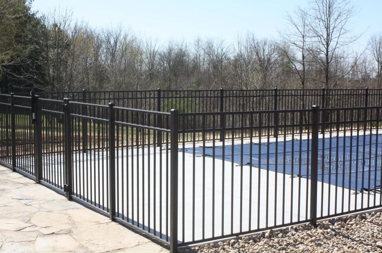 A black metal fence surrounds a swimming pool.