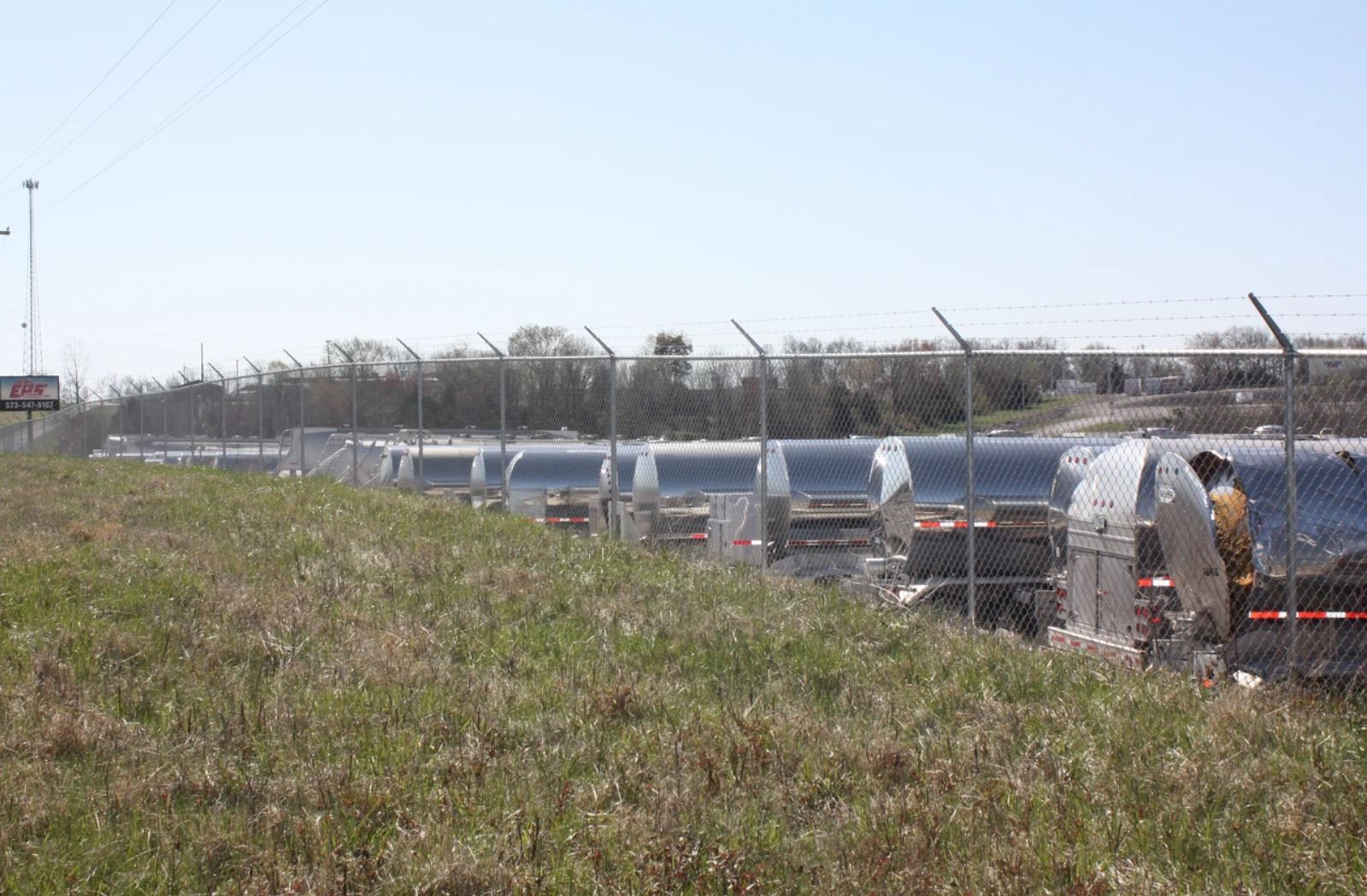 A fenced in field with a row of trailers in the background