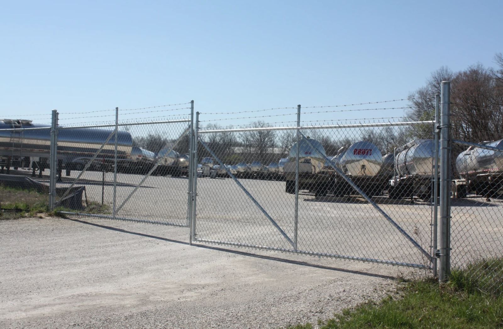 A chain link fence surrounds a parking lot with trucks parked behind it