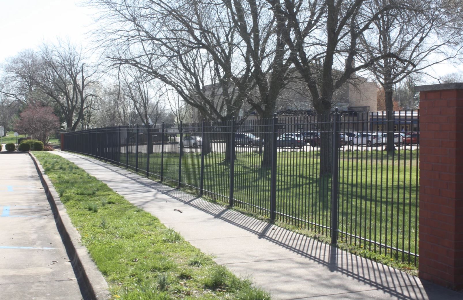 A wrought iron fence along a sidewalk in a park