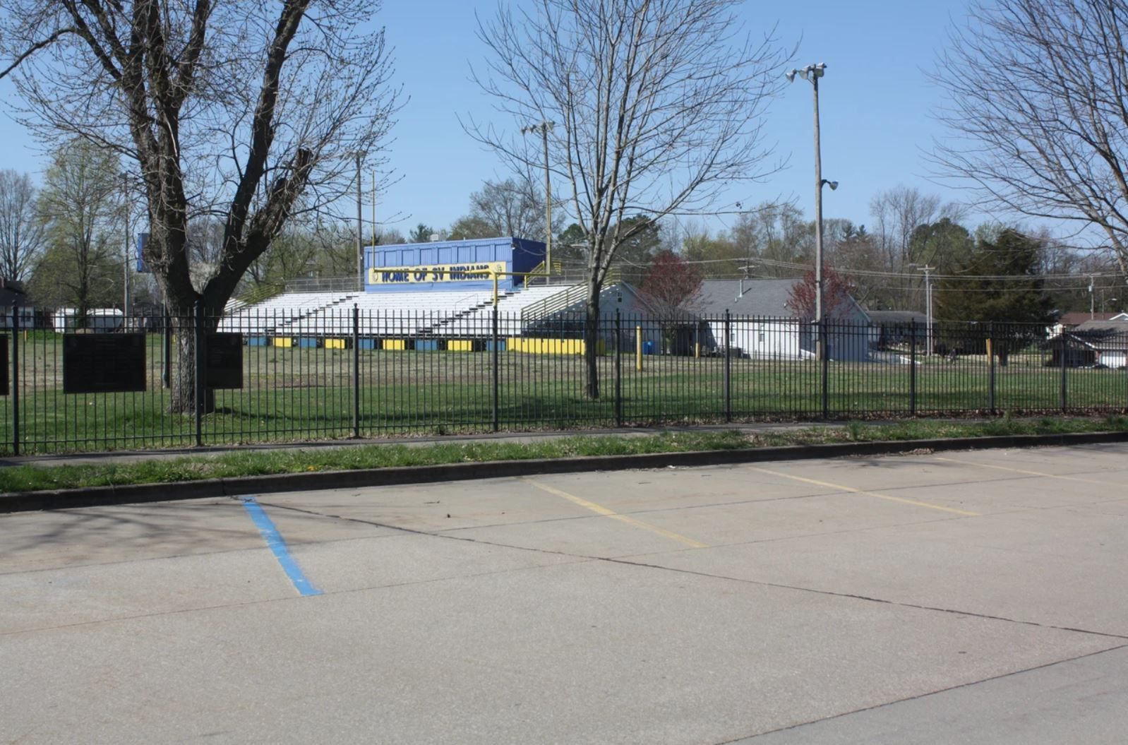 A parking lot with a fence and a stadium in the background
