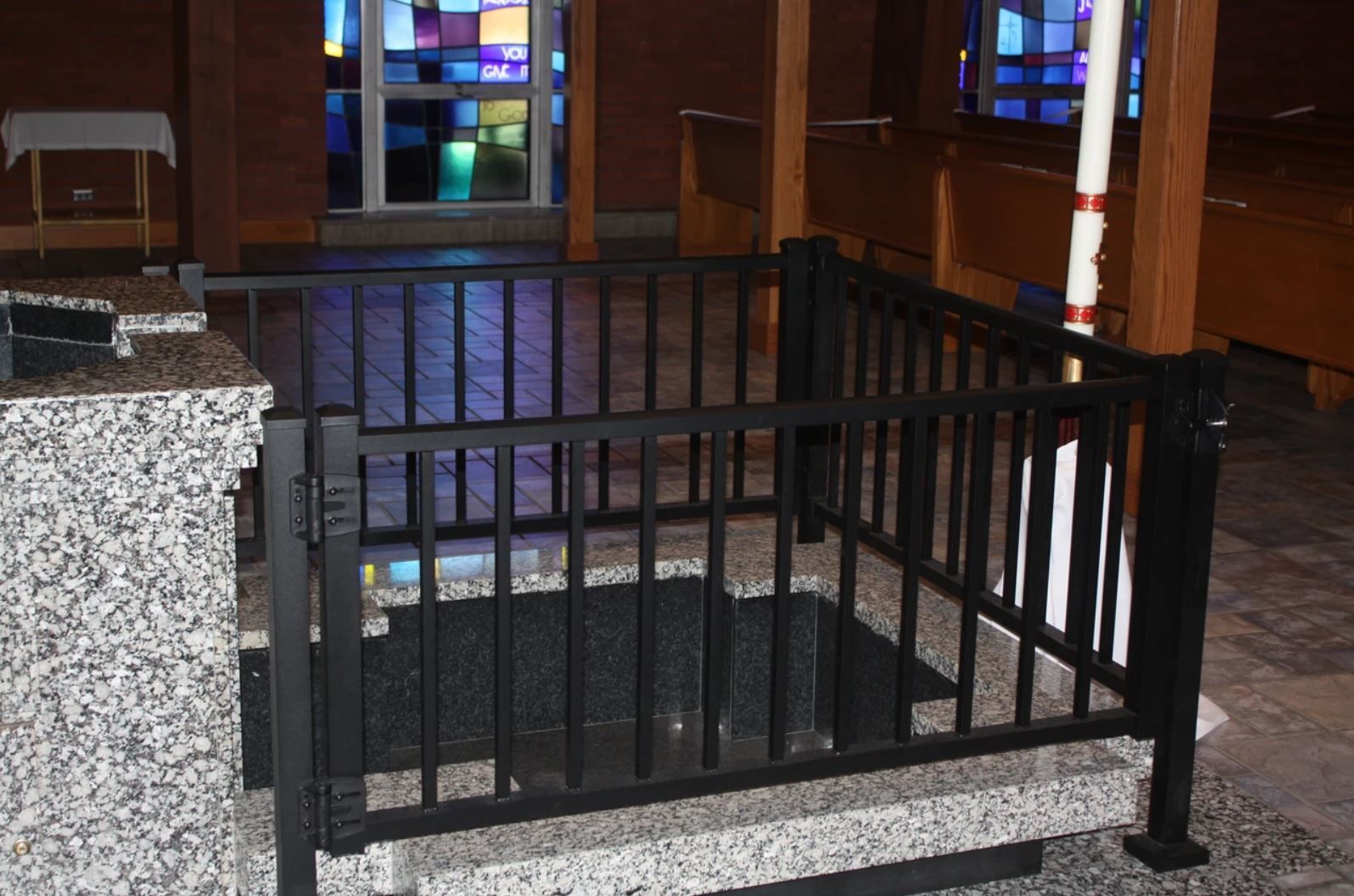 A black fence surrounds a stone altar in a church