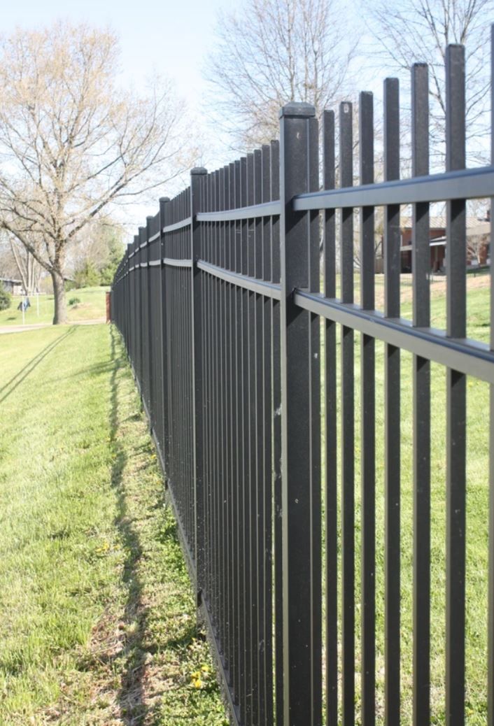 A black metal fence surrounds a grassy field.