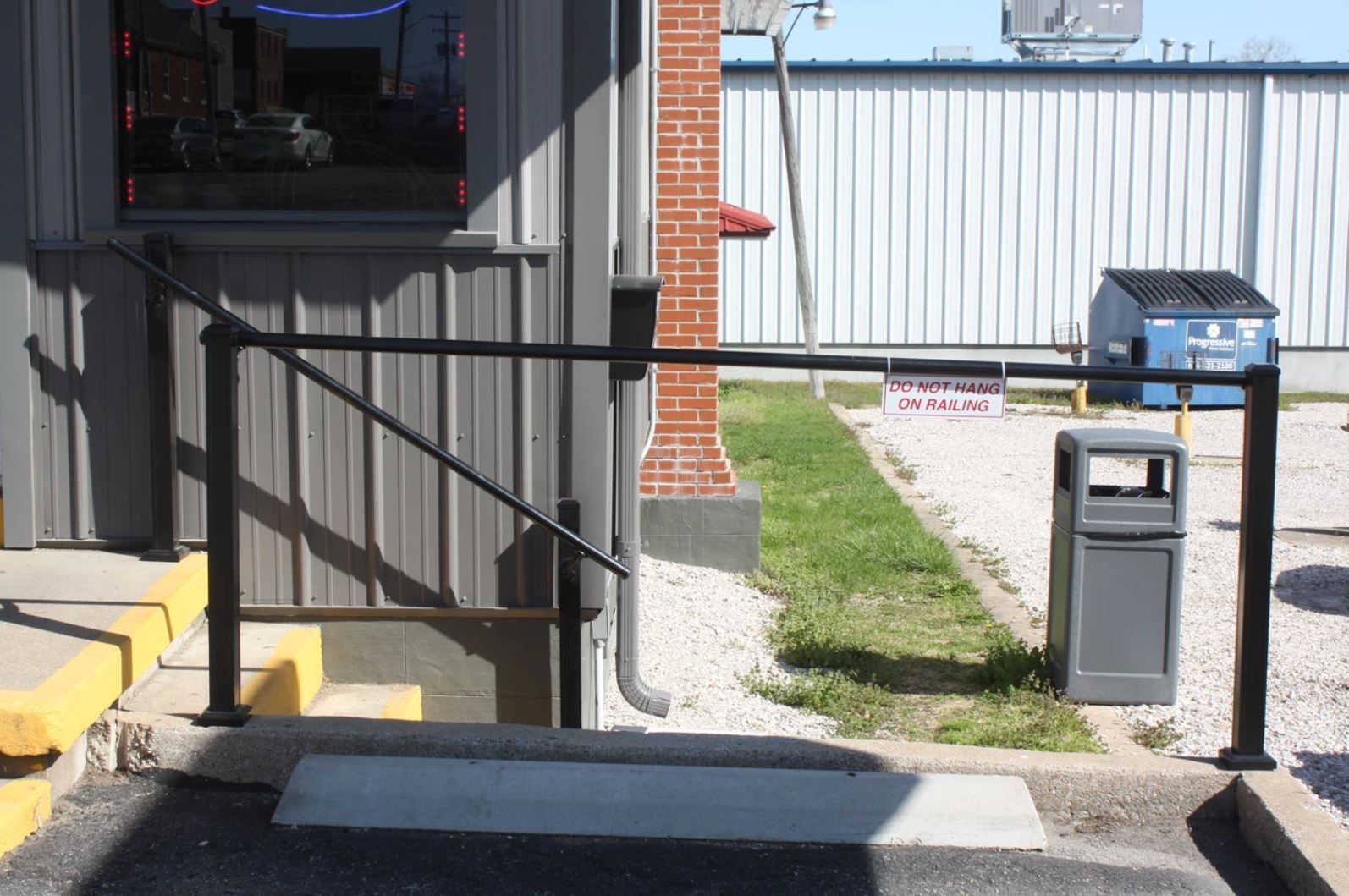 A building with stairs and a trash can in front of it