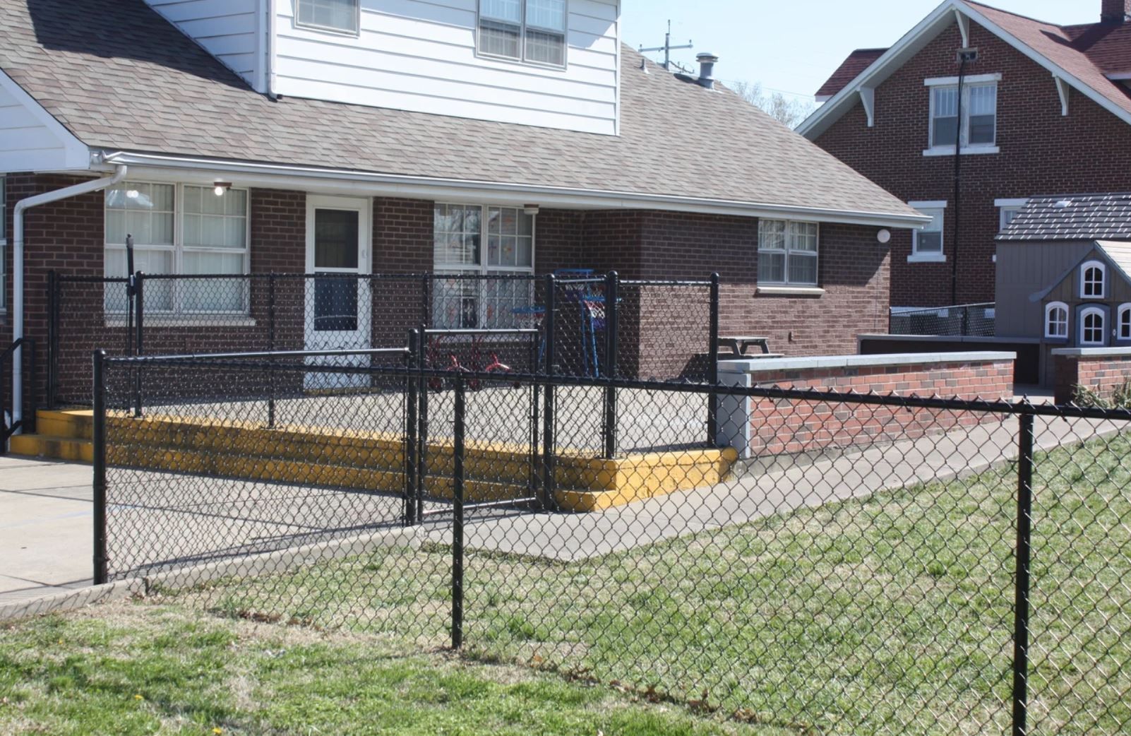 A chain link fence is in front of a brick house