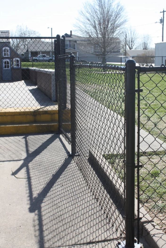 A chain link fence with a gate leading to a park
