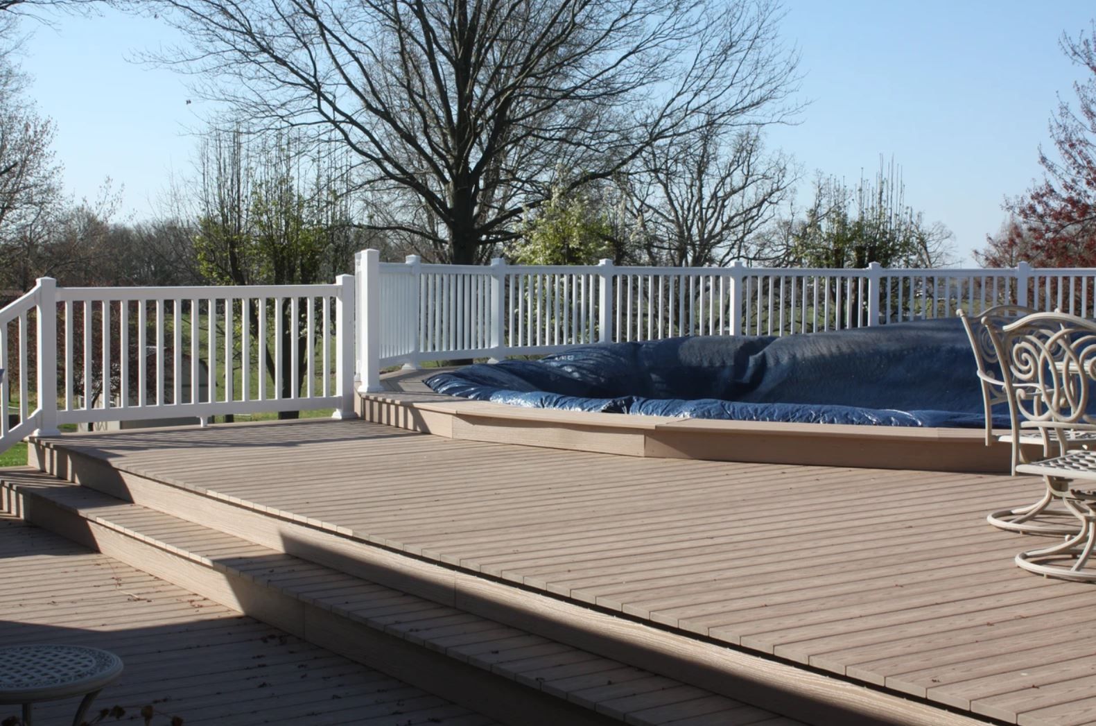 A deck with a white railing and a hot tub