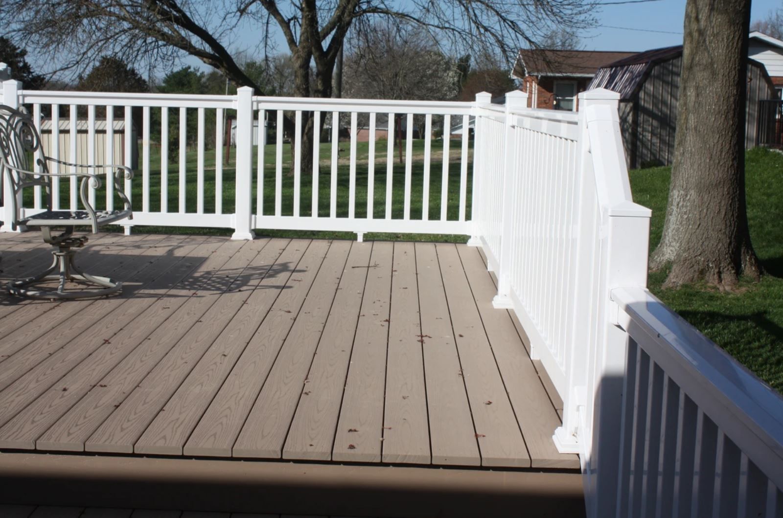 A deck with a white railing and chairs on it