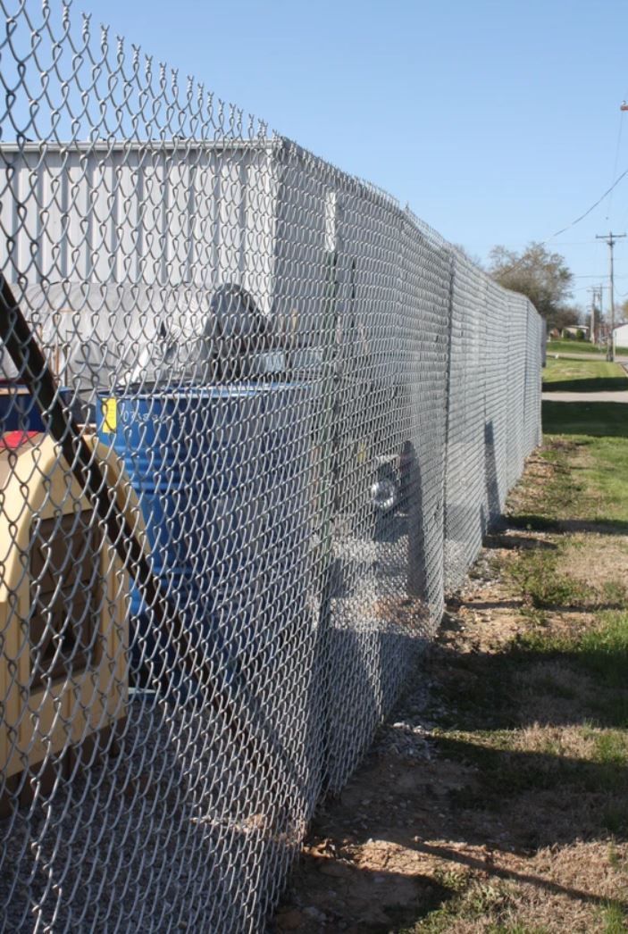 A chain link fence with barbed wire along the side of it.