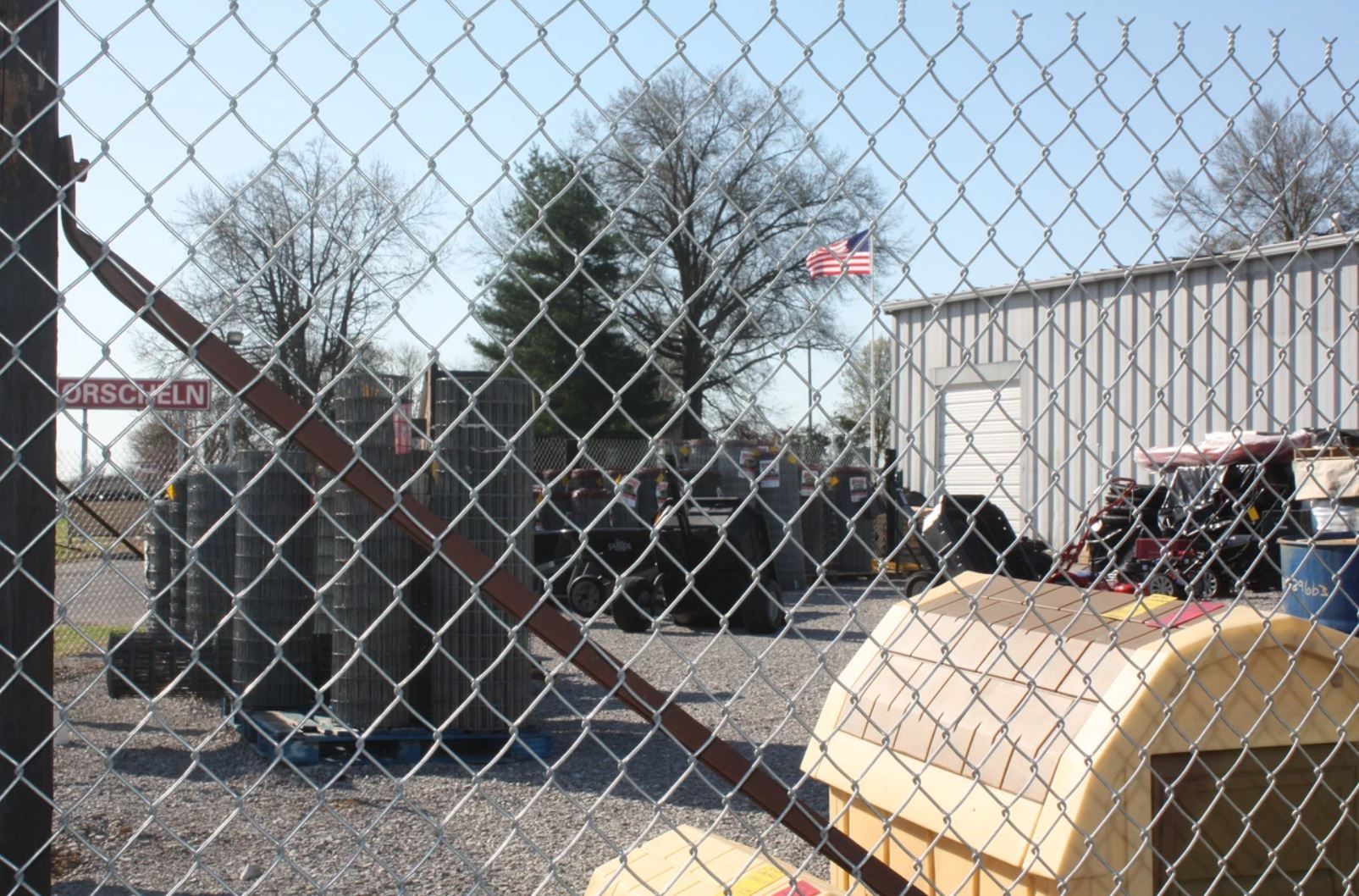 A chain link fence surrounds a building with a sign that says ' no parking ' on it