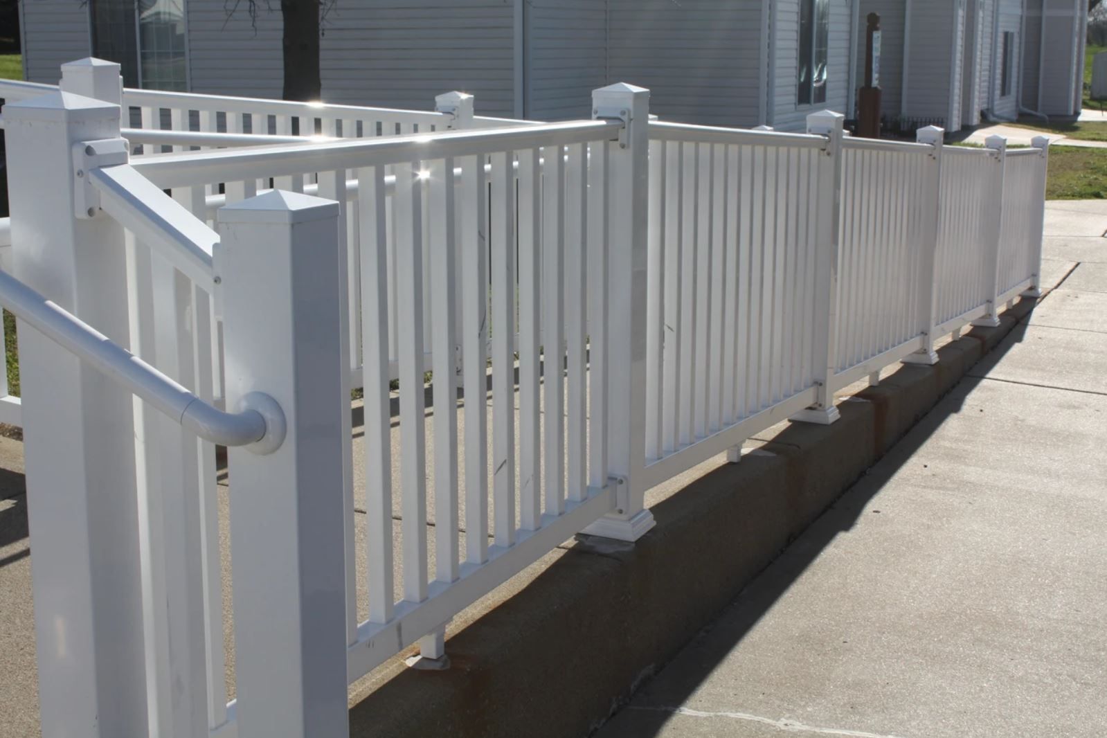 A white fence with a railing on the side of it
