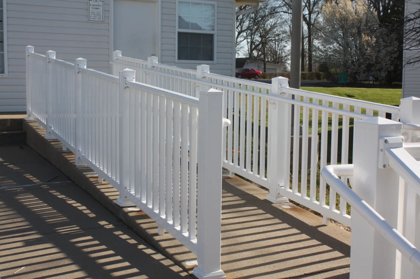 A white fence surrounds a ramp leading to a house.