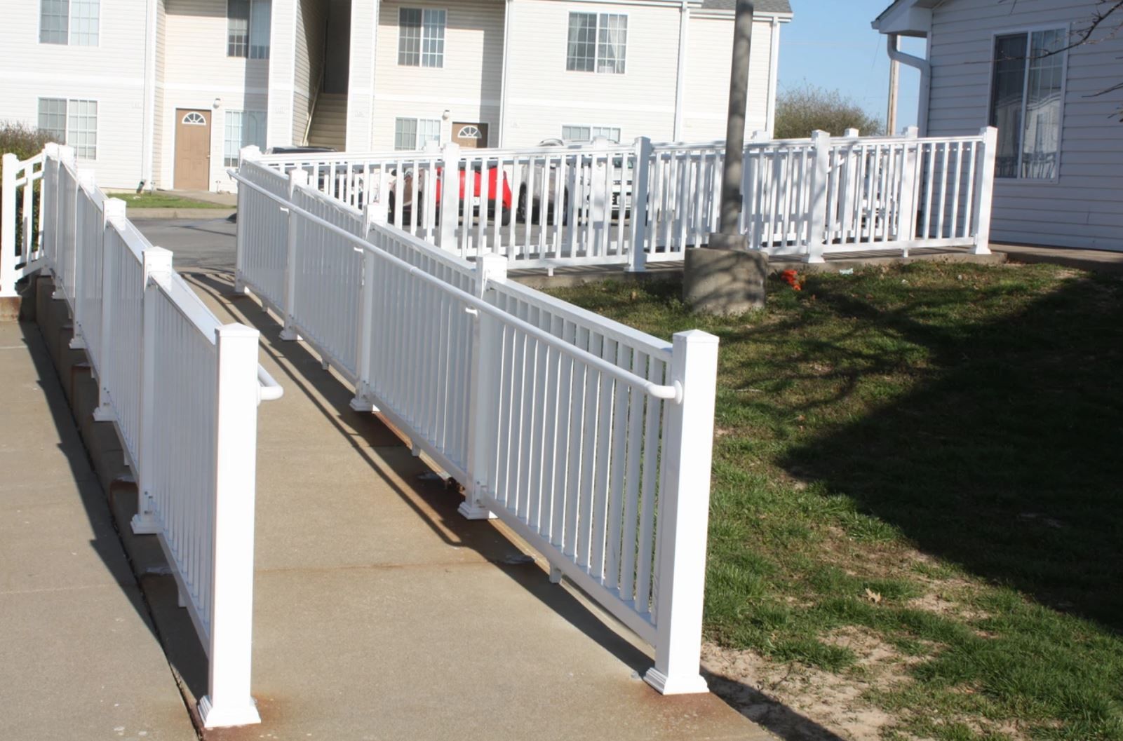 A white fence surrounds a ramp leading to a house