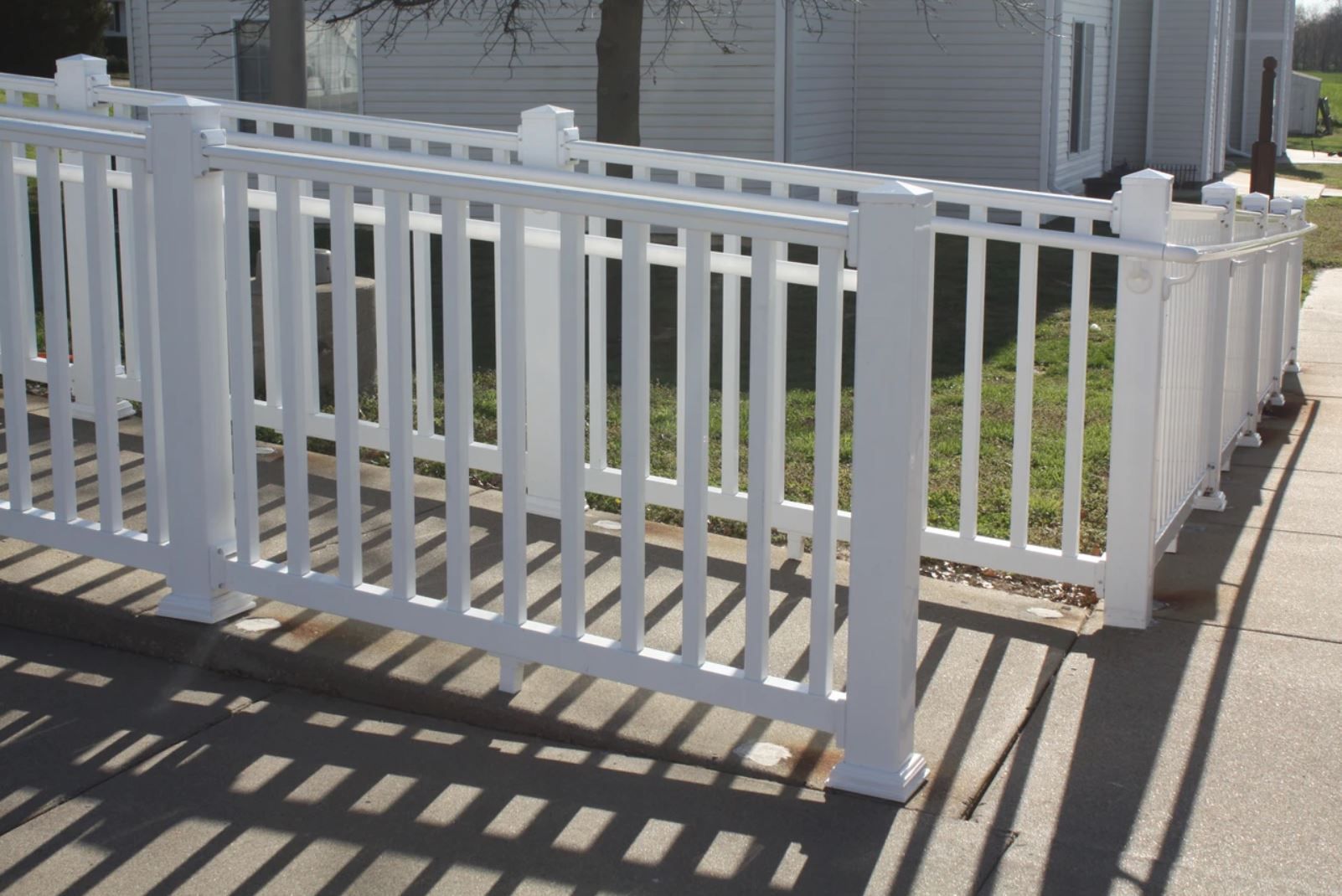 A white fence is sitting on the sidewalk in front of a house.