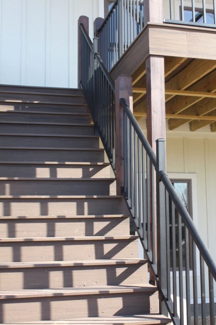 A set of wooden stairs with a metal railing