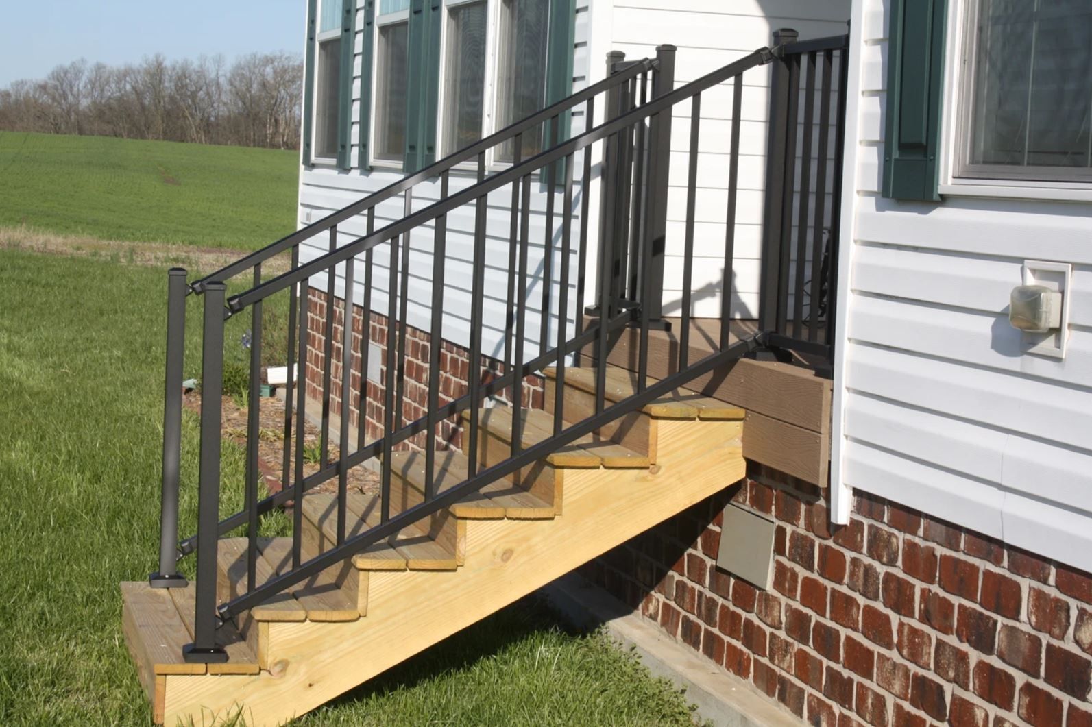 A wooden staircase with a metal railing on the side of a house