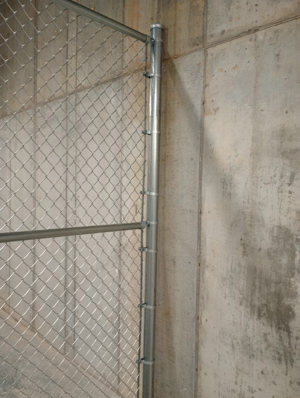 A chain link fence is attached to a concrete wall