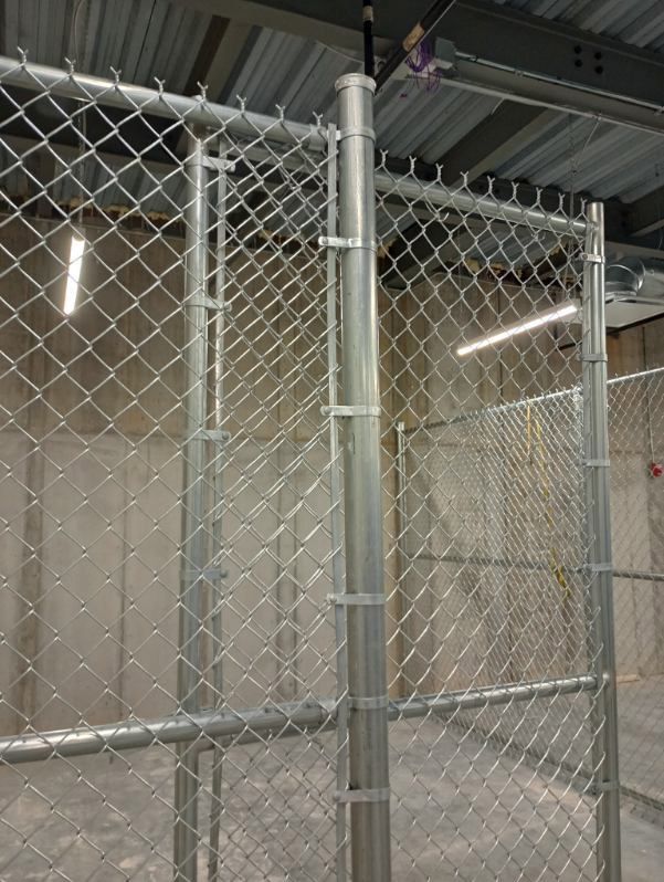 A chain link fence is in a room with concrete walls