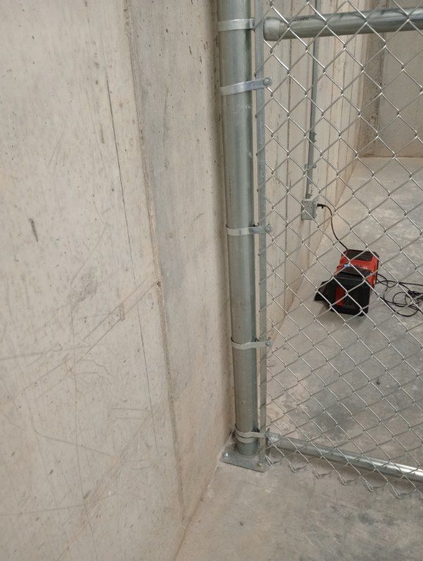 A chain link fence attached to a concrete wall