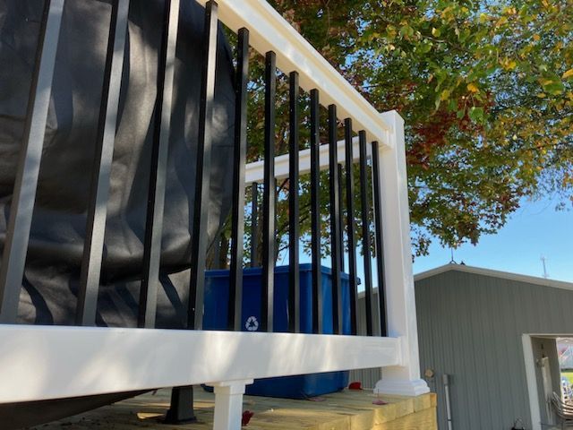 A white railing with black bars on a deck