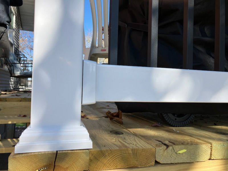 A close up of the white railing on a wooden deck