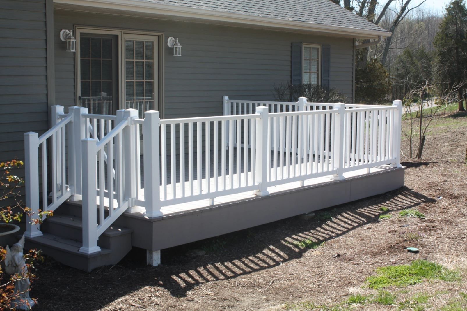 A white deck with stairs is in front of a house.