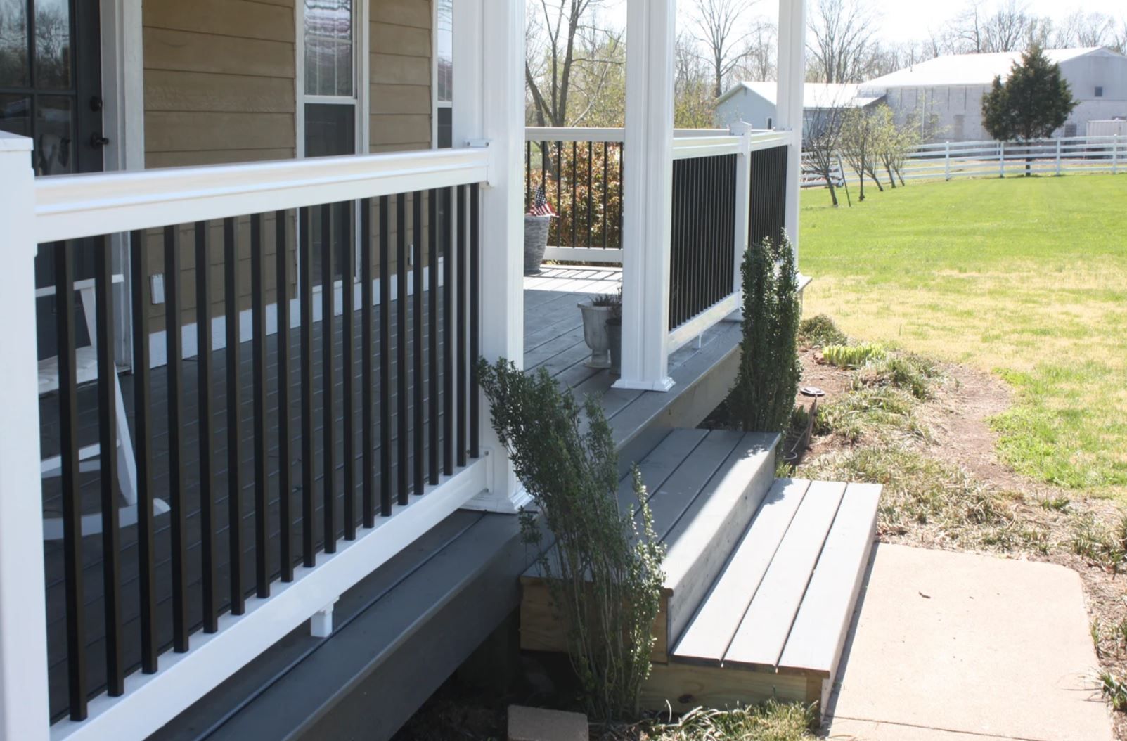 A porch with a white railing and a bench