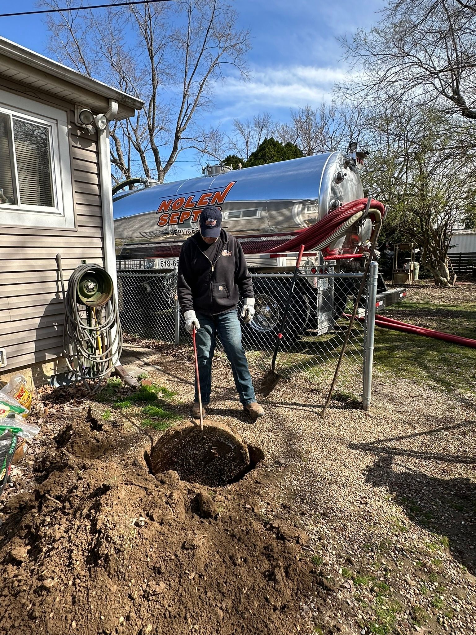 a man is digging a hole in the dirt in front of a house .