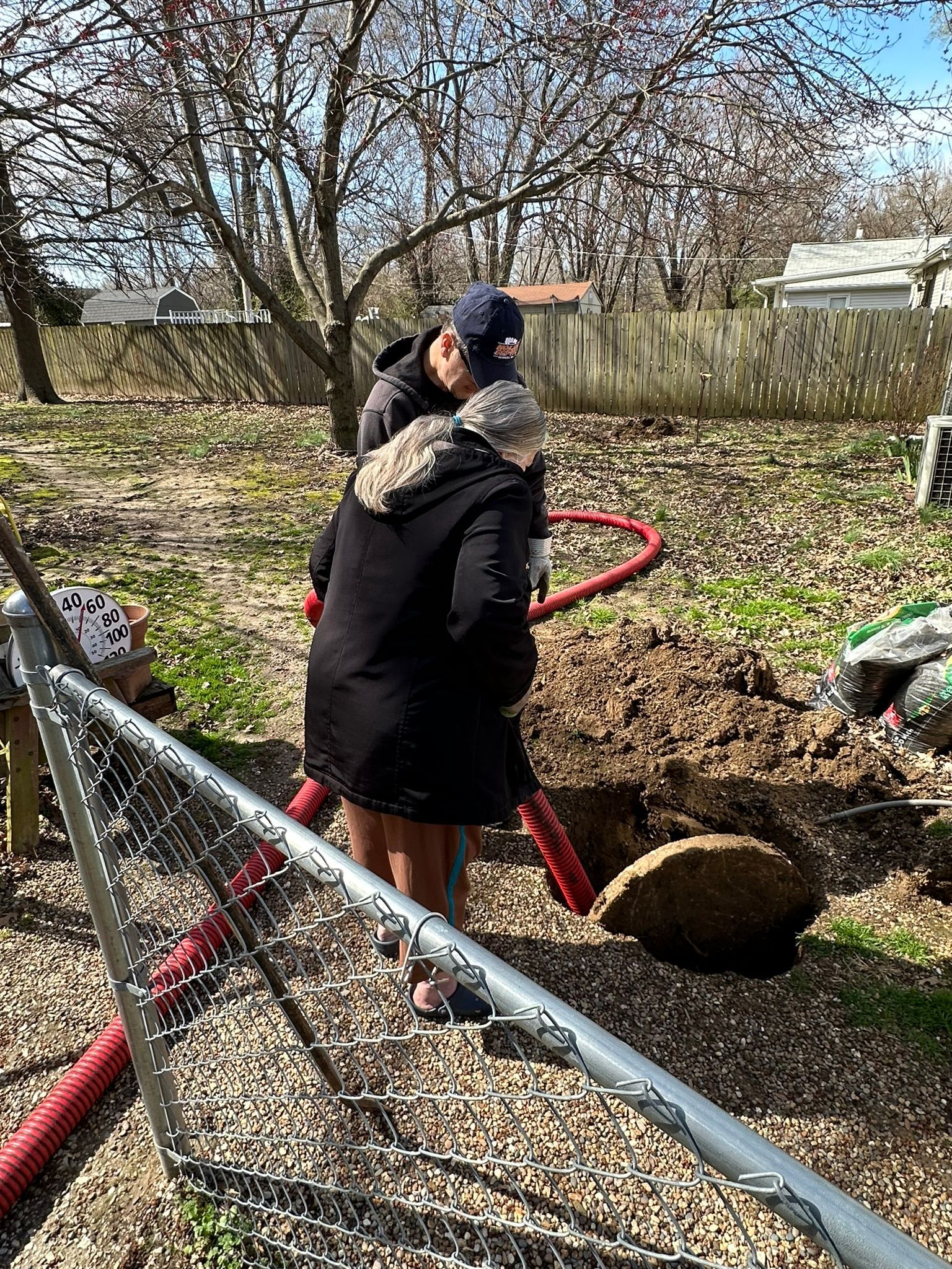 a man and a woman are standing next to a hole in the ground .