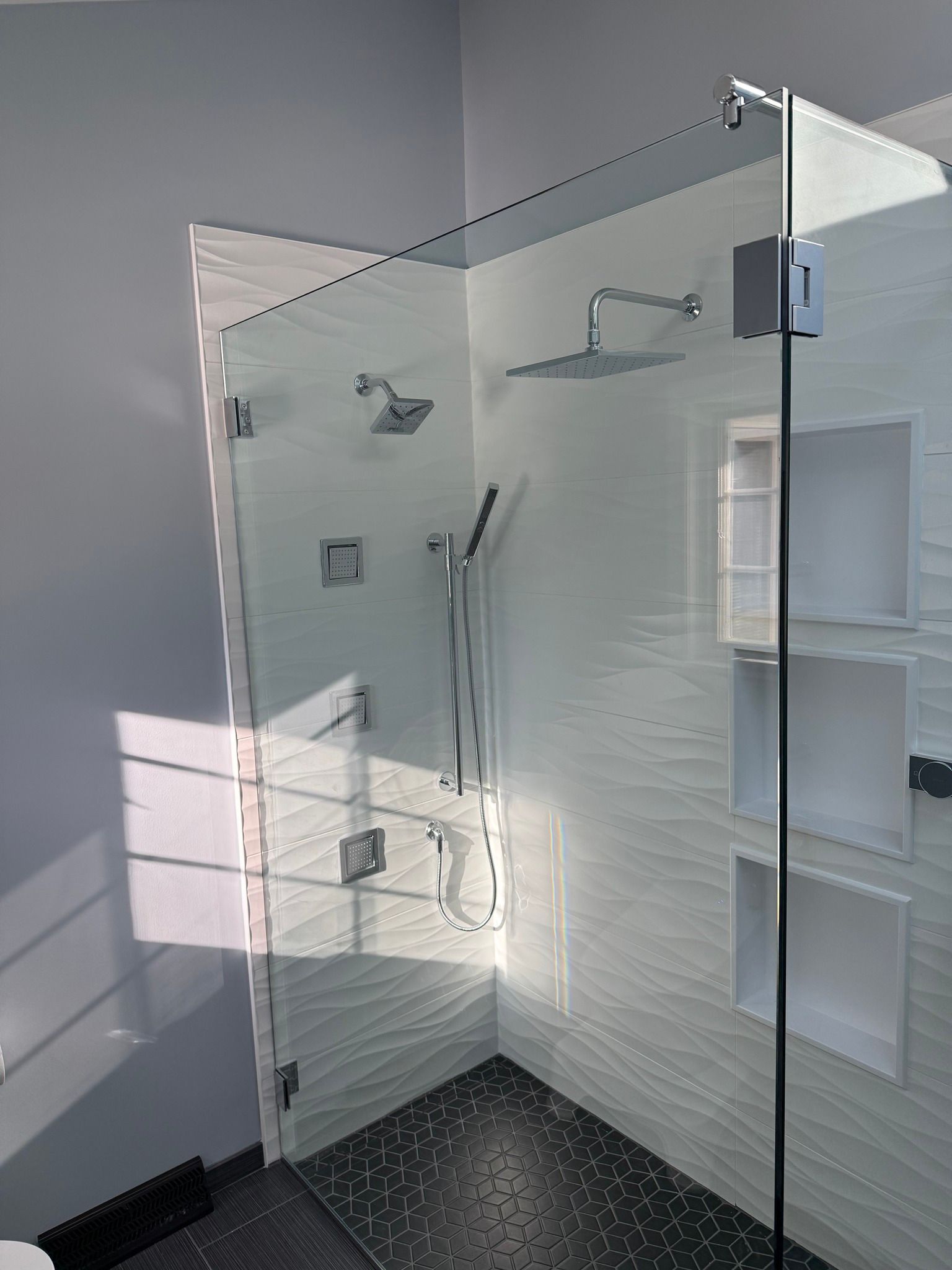 A bathroom with a walk in shower with a glass door.