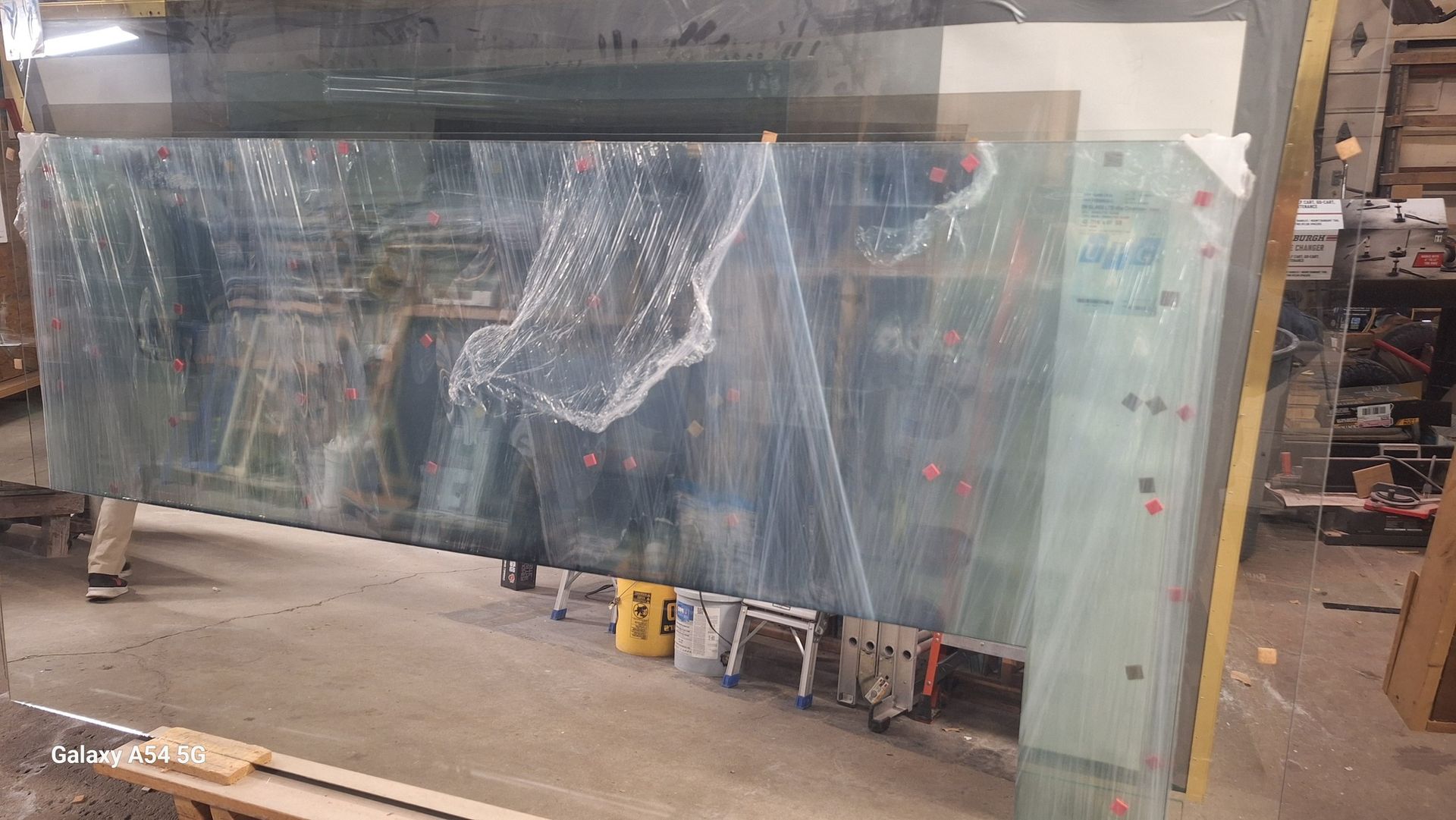 A large piece of glass is sitting on top of a wooden pallet in a warehouse.