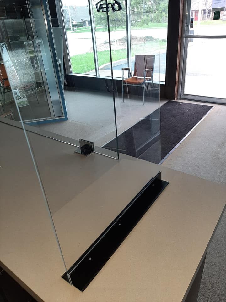 A glass barrier is sitting on top of a table in a room.