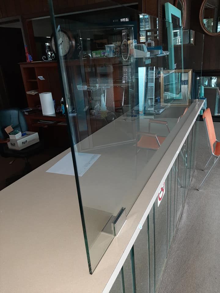 A glass barrier is sitting on top of a counter in a room.