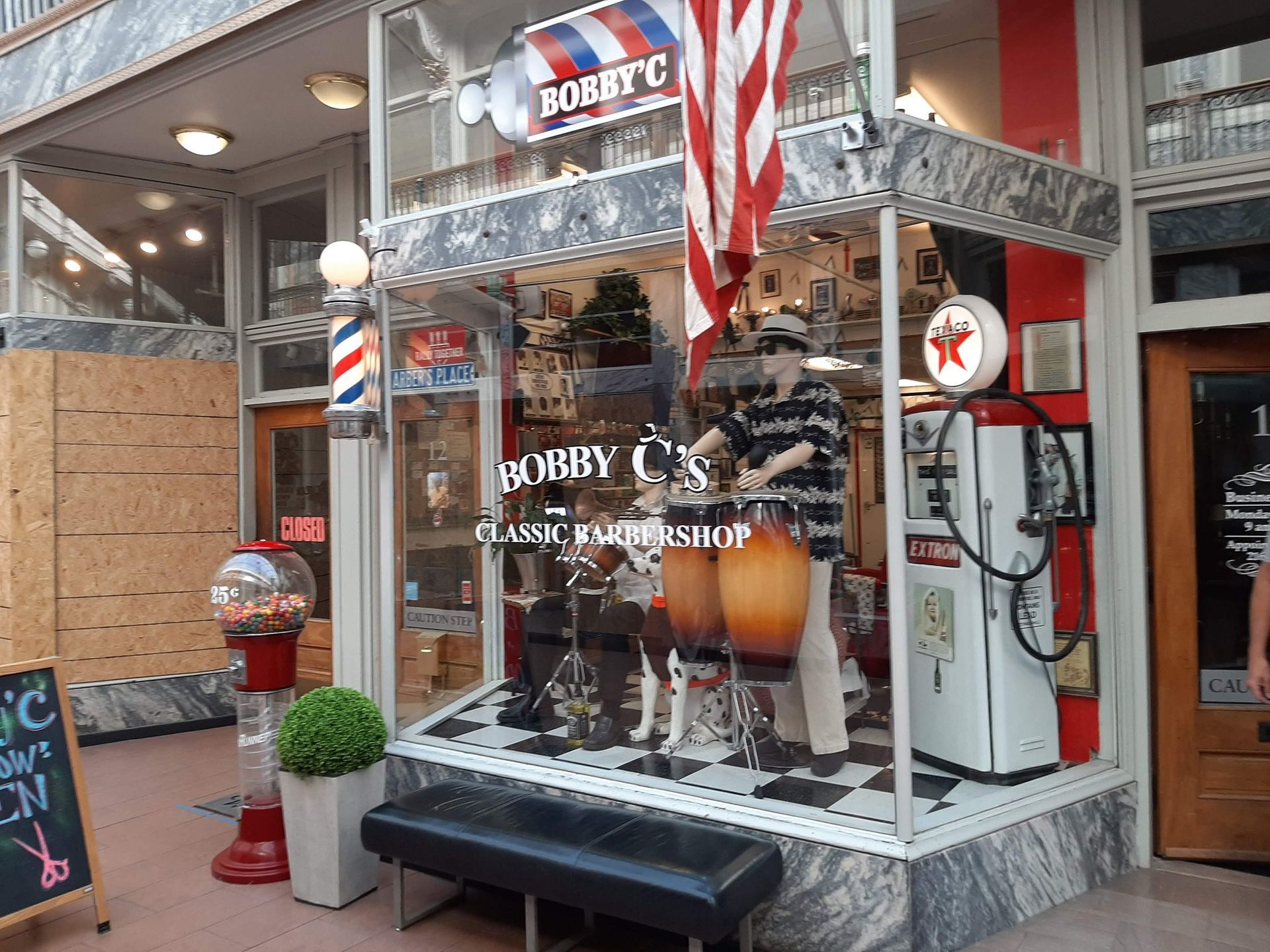 A barber shop with a gas pump in front of it.