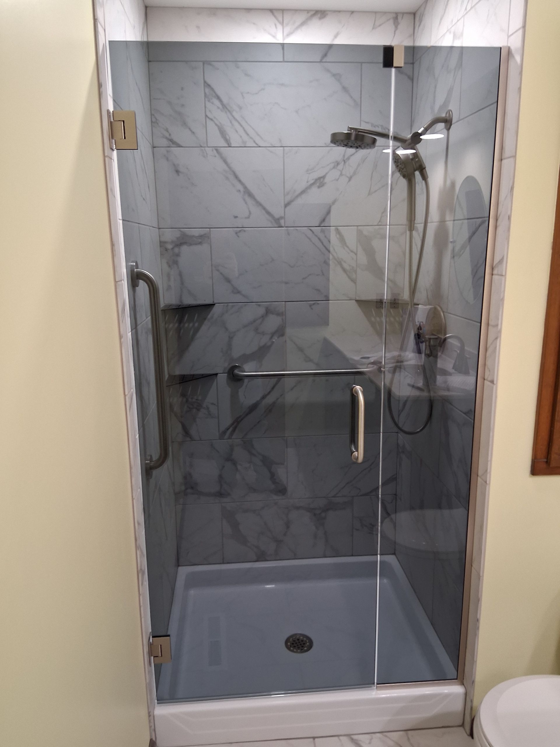 Glass shower enclosure with gray marble tile, chrome fixtures, and a gray shower base.