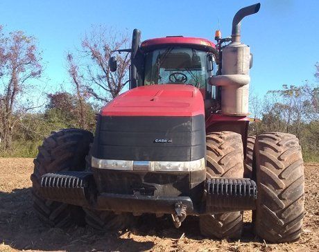 a red case tractor is parked in a dirt field
