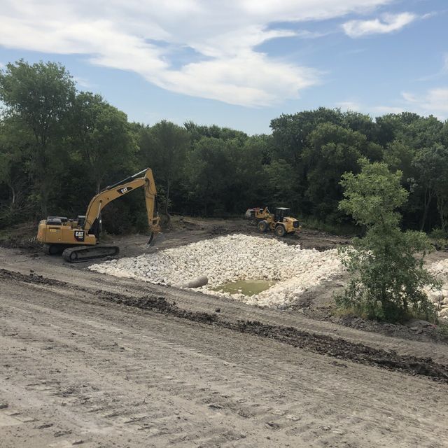 a large yellow excavator is working on a dirt road .