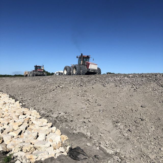two tractors are parked on top of a dirt hill