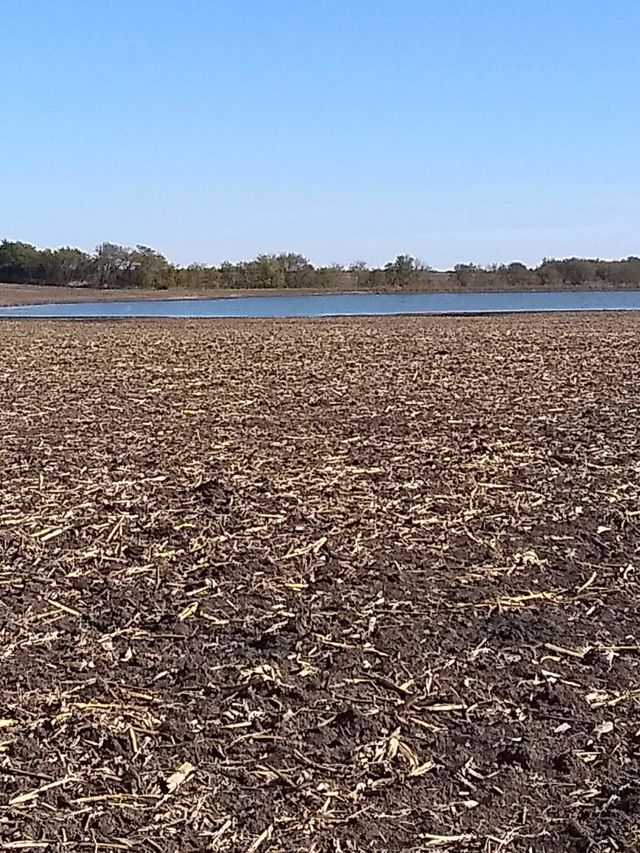 there is a large field with a lake in the background .