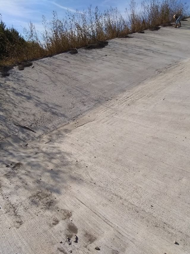 a concrete road with grass on the side of it