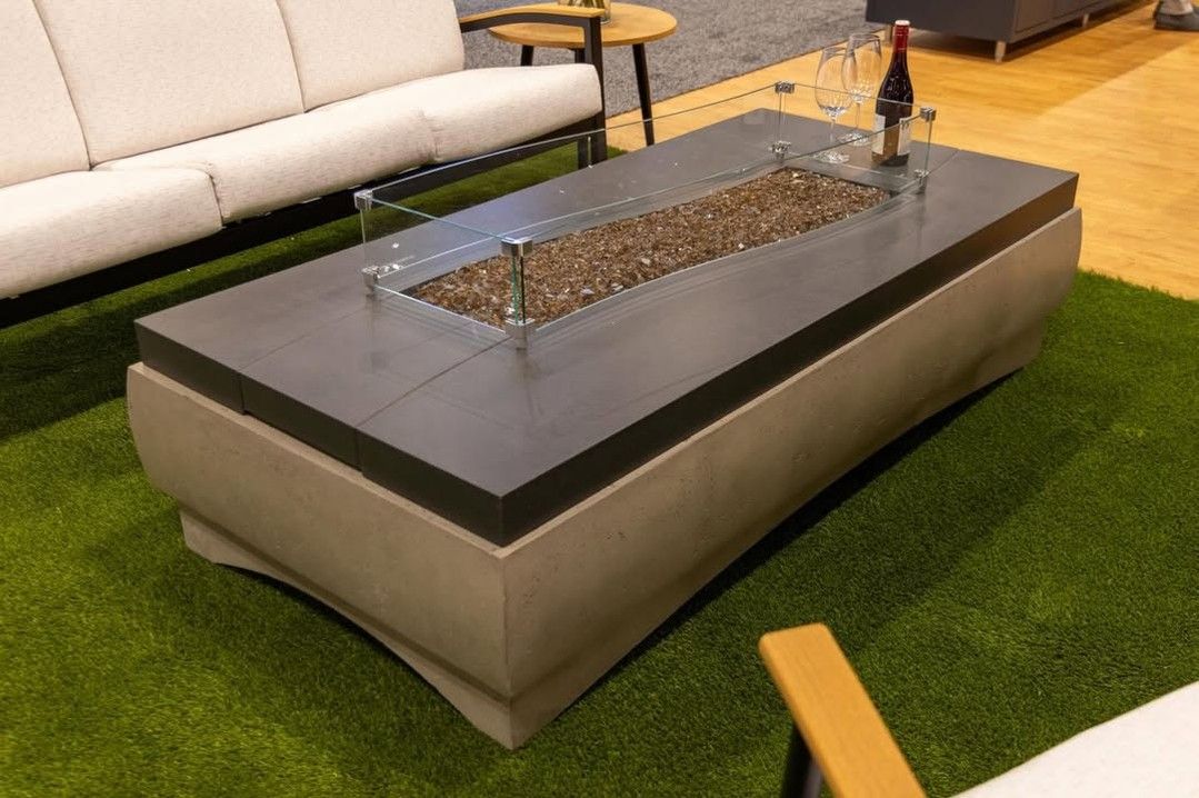 Modern outdoor fire pit table with water feature on artificial grass in a patio showroom