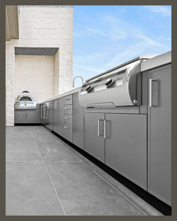 Modern outdoor kitchen with gray cabinets and built-in grill on a tiled patio