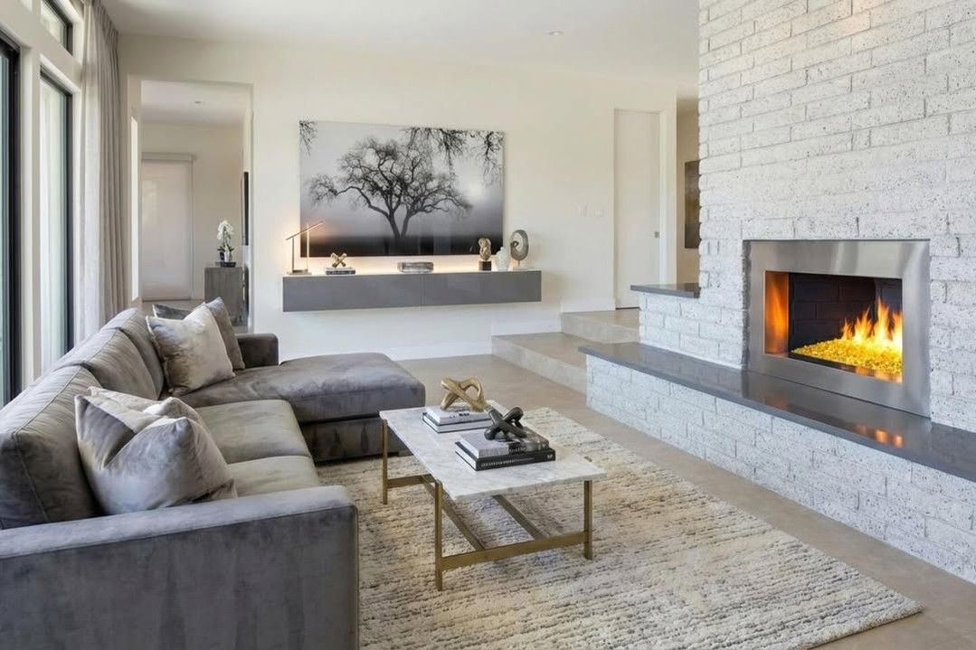 Modern living room with gray sectional, white brick fireplace, and soft neutral decor