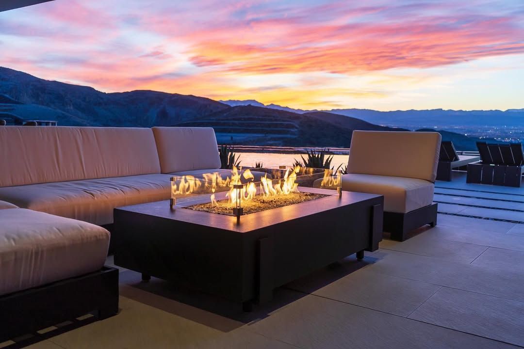 Outdoor patio lounge with fire pit at sunset overlooking the water