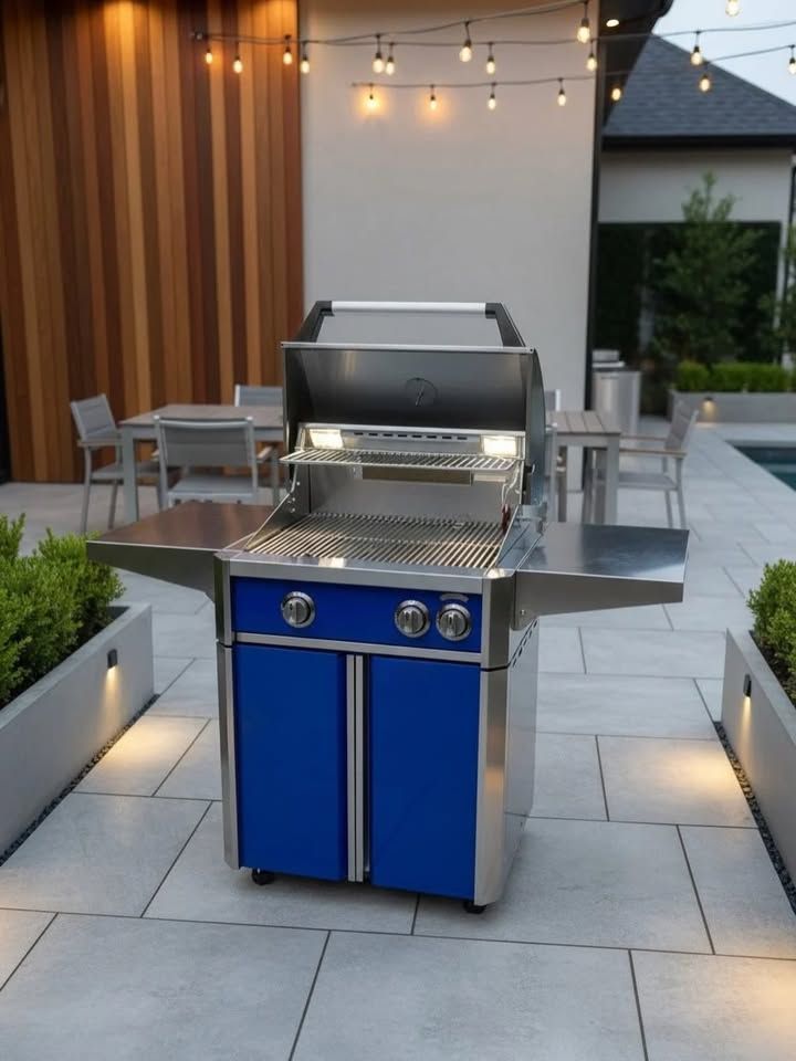 Blue outdoor gas grill on a patio with string lights and dining tables in the background