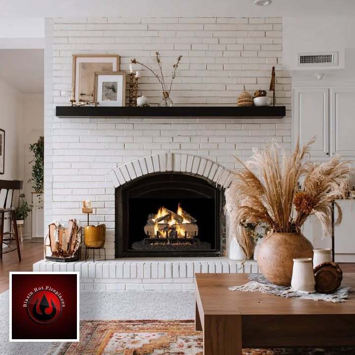 Cozy living room with white brick fireplace, lit fire, black mantel, and dried pampas grass decor