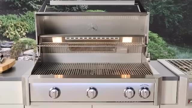 Stainless steel outdoor gas grill on a patio, with three control knobs and side shelves.